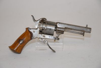 a close up of a revolver with a wooden handle on a white surface