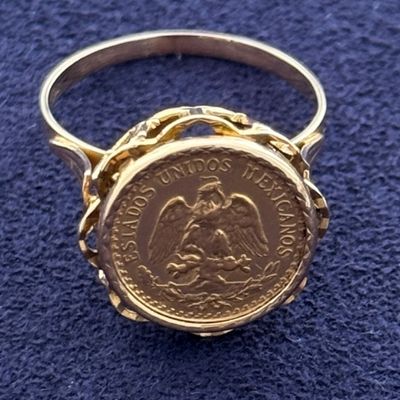 a close up of a gold ring with a coin on it