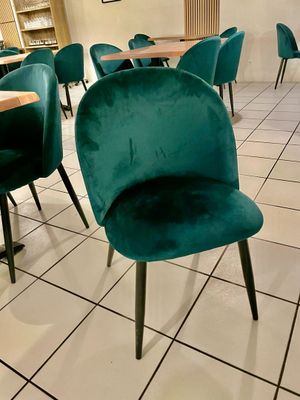 Des tables et des chaises sont alignées dans une pièce au sol carrelé.