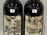 two bottles of red wine sitting next to each other on a white surface