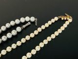 a close up of a necklace with pearls on a black surface
