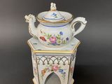 a white tea pot sitting on top of a small stand