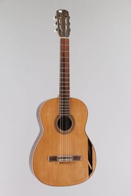 une guitare accrochée au mur d'une pièce aux murs blancs