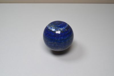a blue marble ball sitting on a white surface