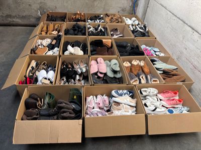 plusieurs paires de chaussures dans une boîte en carton posée sur le sol