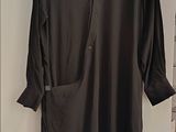 black shirt hanging on a hanger in a white room