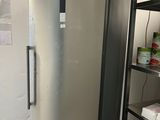 a silver refrigerator in a room with shelves of food
