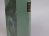 an old book with a green cover sitting on top of a white table