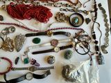 many different types of necklaces and bracelets laid out on a table