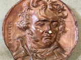 a picture of a bronze medallion with a man ' s face on it