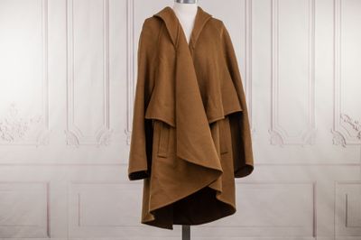 Le manteau est marron et est muni d'une capuche.