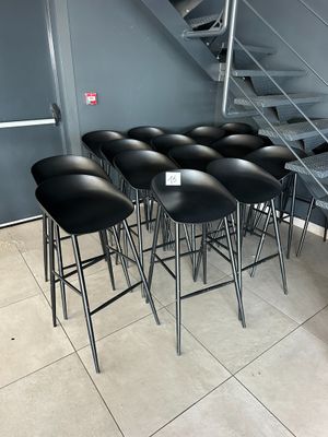 several black stools sit in front of a staircase in a room