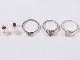 three rings and a pair of earrings are sitting on a white surface