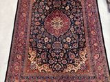 a close up of a rug on a floor with a chair in the background