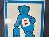 une pancarte bleue et blanche représentant un ours tenant une valise