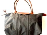 black leather handbag with brown leather handles on a white background