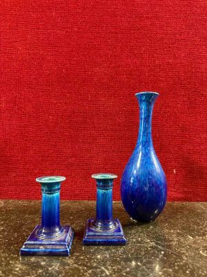three blue vases sitting on a table next to a red wall