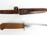 an old knife and a leather sheath on a white surface