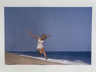 photograph of a woman jumping in the air on a beach