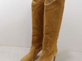 une paire de bottes de cow-boy en daim beige posées sur une surface blanche