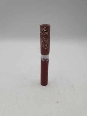 un gros plan d'un tube de rouge à lèvres posé sur une surface blanche
