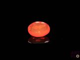 an orange diamond in the dark with a reflection on the surface
