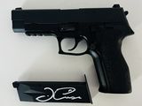 a black gun with a signature on it next to a box of cigarettes