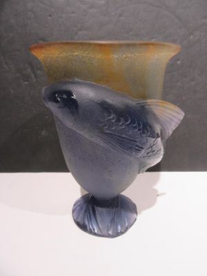 a glass vase with a bird on it sitting on a table