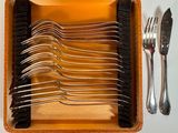 plusieurs fourchettes et cuillères dans un étui, ainsi qu'une fourchette et un couteau posés sur une table