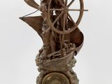 statue représentant un homme sur un bateau, avec un gouvernail et une horloge