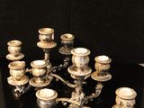 a silver candelier with twelve candles on a black table