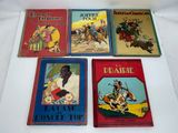 several children ' s books are lined up on a white surface