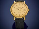 a gold plated wrist watch with a black leather strap