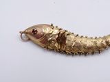 a gold fish brooch on a white surface