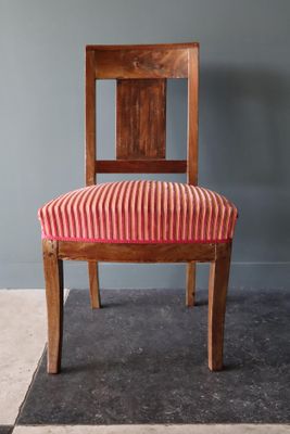 une image représentant une chaise en bois dont l'assise est recouverte d'un tissu rayé rouge et blanc