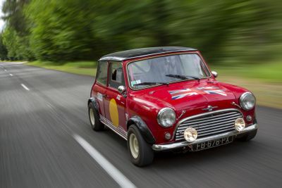 a small red car that is driving down the road
