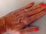 a woman ' s hand with red nails and a ring on it