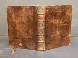 an old brown book sitting on top of a table next to a gray wall