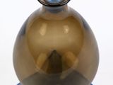 a brown glass vase with a blue lid on a blue stand