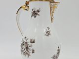 a white pitcher with black flowers on it on a white surface