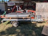 a trailer that is parked in the grass with a truck behind it