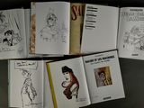 several books are lined up on a table with drawings on them
