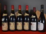 six bottles of wine are lined up on a red table