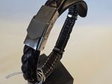 bracelet en cuir noir muni d'un fermoir argenté sur un support noir