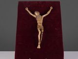 une image représentant un crucifix en or posé sur un socle en velours rouge