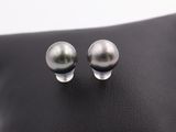 a pair of pearl earrings on a black leather surface