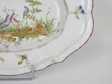 a plate with a bird design on it sitting on a stand