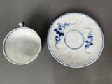a cup and saucer sitting on a table next to each other