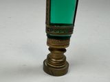 a green glass vase with a gold rim on a white table