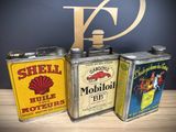 three vintage shell oil cans sitting on top of a wooden table